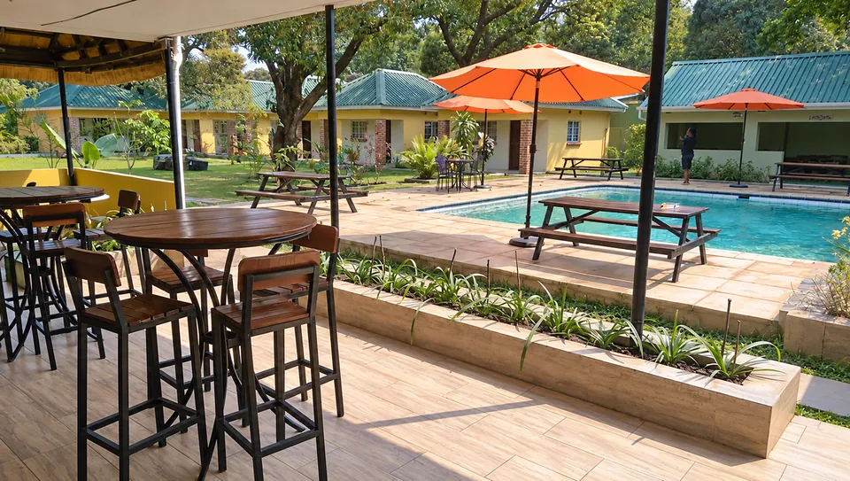 Cafe Zambezi poolside seating with wooden tables, orange parasols and trees, photographed in August 2018