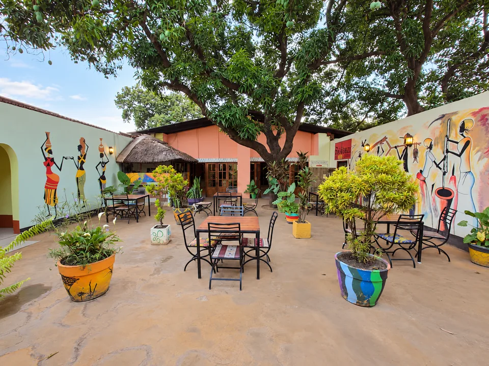 Cafe Zambezi courtyard with colourful African wall murals, leafy trees and outdoor tables
