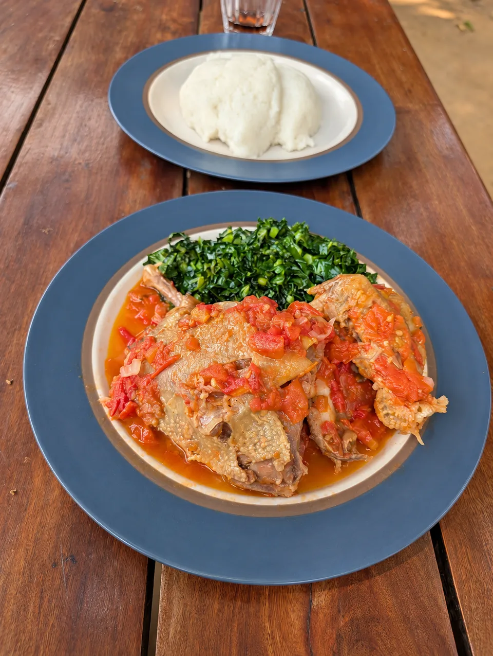 Cafe Zambezi village chicken in tomato sauce with leafy greens and a separate plate of nshima